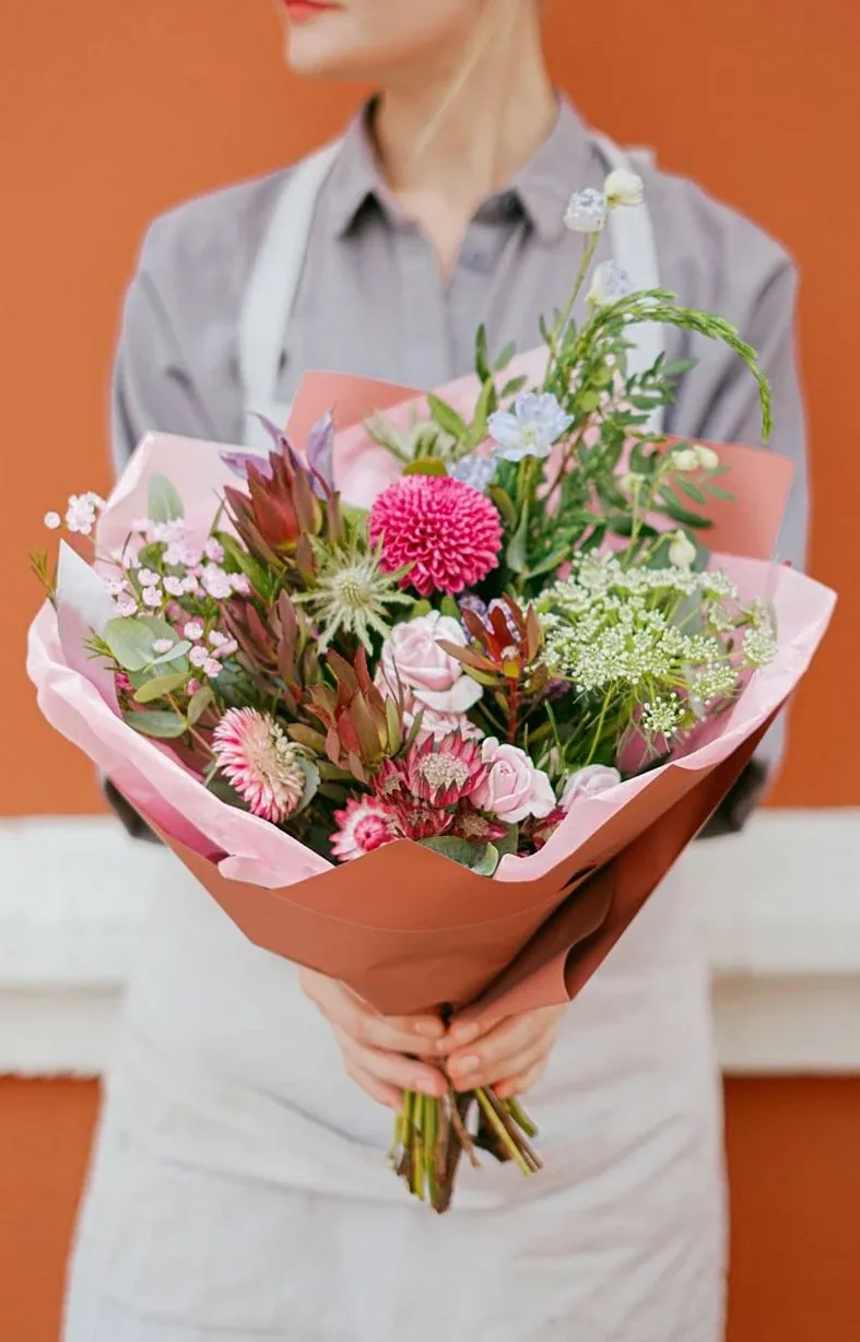 ピンクの花束を抱えたエプロン姿のスタッフ